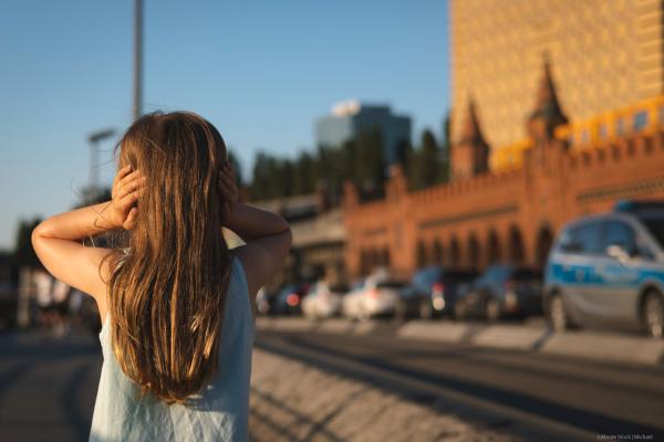 Girl holding her hands over her ears in a busy street